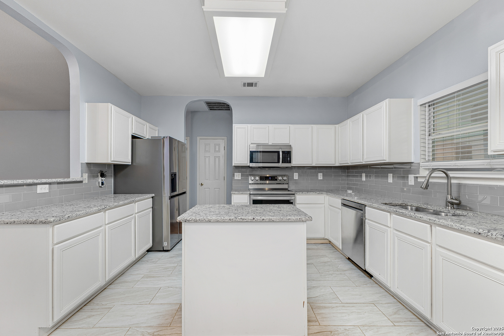 8522 Sonora Pass Helotes, TX 78023 - Photo 11 of 27 a kitchen with stainless steel appliances granite countertop a sink dishwasher a refrigerator and white cabinets with wooden floor