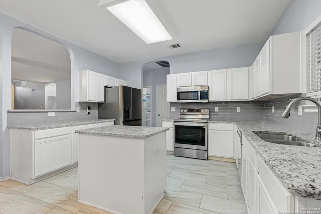 a kitchen with granite countertop a sink stove and microwave