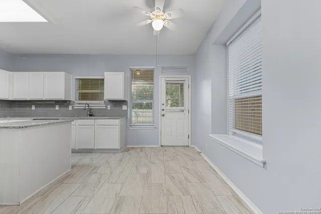 a large white kitchen with cabinets a sink and dishwasher