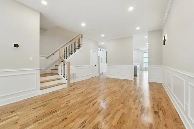 a view of an empty room with wooden floor and stairs