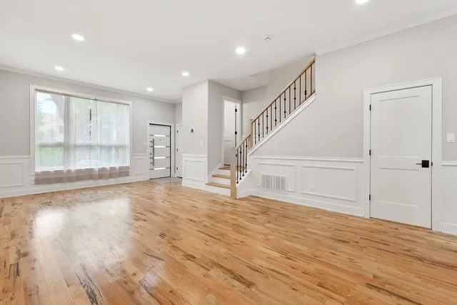 a view of an empty room with wooden floor and windows