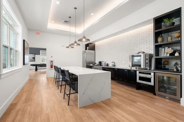 a kitchen with stainless steel appliances kitchen island granite countertop a stove top oven a sink a dining table and chairs with wooden floor