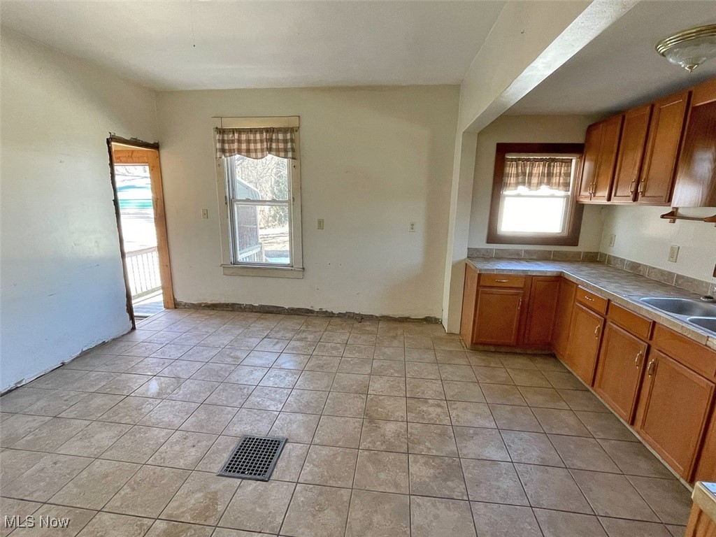 2703 Mahoning Road Northeast Canton, OH 44705 - Photo 9 of 21 Kitchen with light tile patterned flooring, light countertops, visible vents, brown cabinets, and a sink