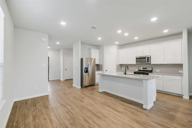 a view of kitchen with granite countertop wooden floor stainless steel appliances and sink