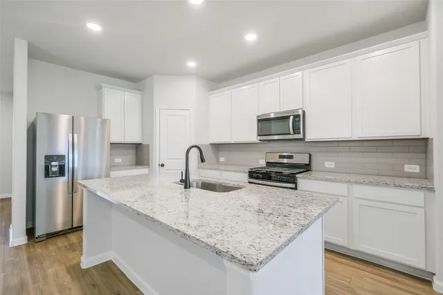 a kitchen with stainless steel appliances granite countertop a sink stove microwave and refrigerator