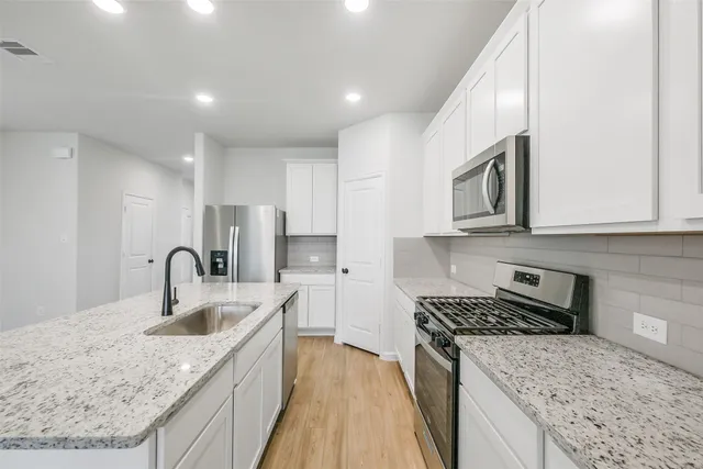 a kitchen with stainless steel appliances granite countertop a sink stove and refrigerator
