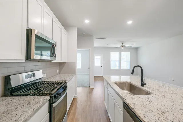 a kitchen with granite countertop a stove a sink and a microwave