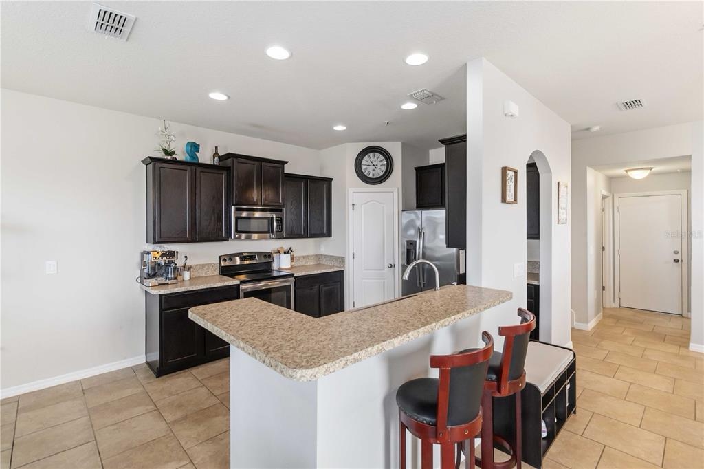 6560 South Goldenrod Road, Unit 79C Orlando, FL 32822 - Photo 12 of 36 a kitchen with stainless steel appliances kitchen island granite countertop a refrigerator and a stove top oven