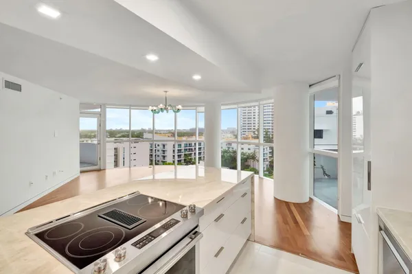 a large kitchen with stainless steel appliances granite countertop a stove and a view of living room