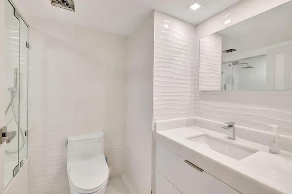 a bathroom with a bathtub shower sink vanity and toilet