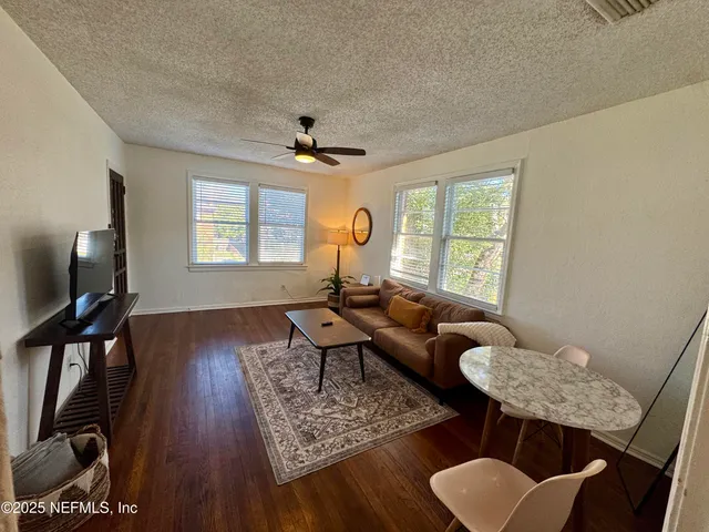 a living room with furniture two window and wooden floor