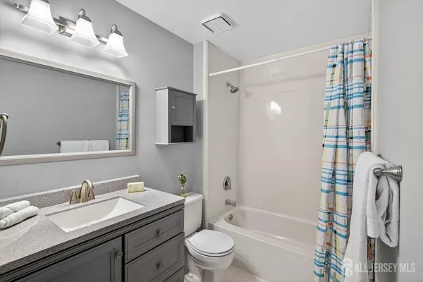 a bathroom with a granite countertop sink a toilet and shower