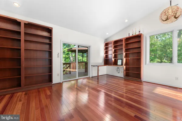 a view of an empty room with wooden floor and a ceiling fan