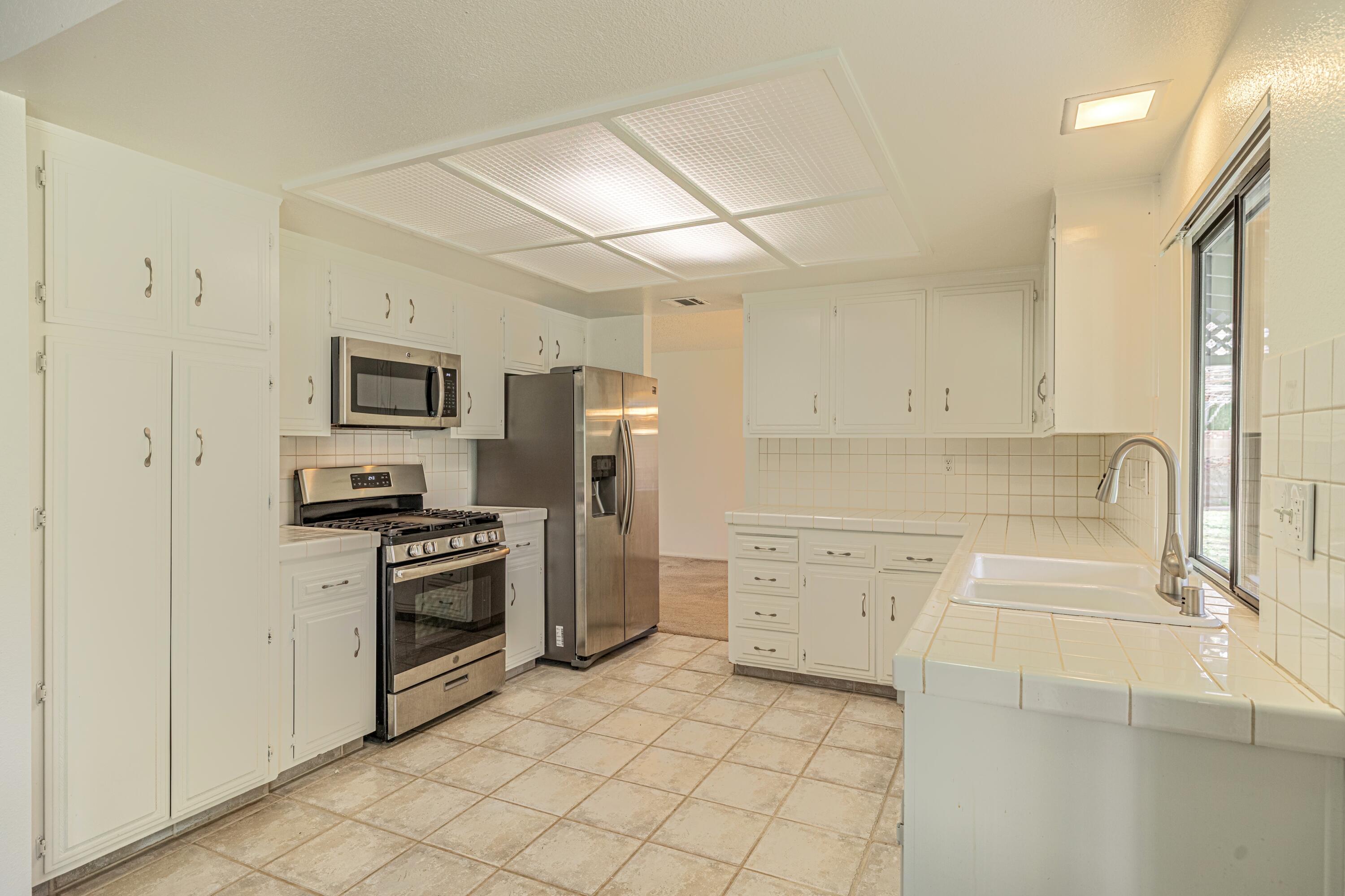 431 Fantasy Street Palmdale, CA 93551 - Photo 3 of 24 a kitchen with white cabinets and stainless steel appliances