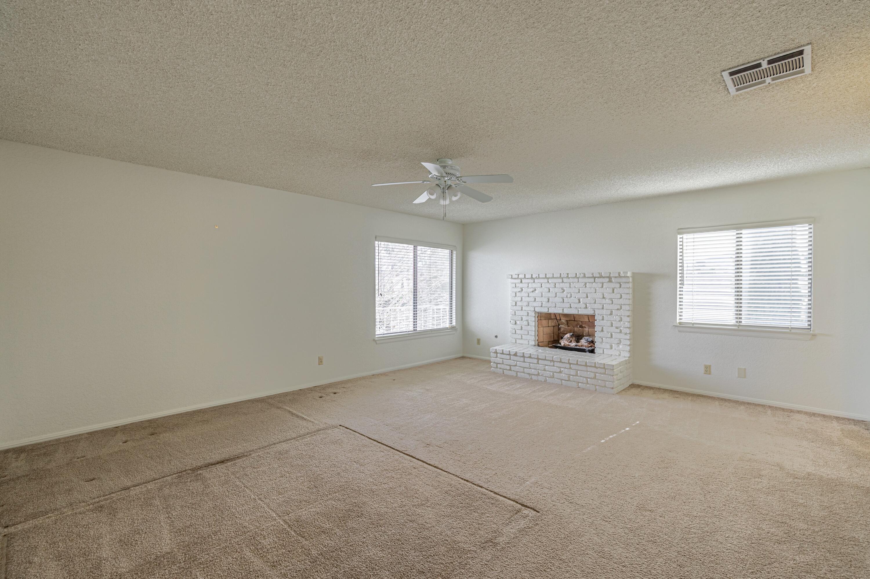 431 Fantasy Street Palmdale, CA 93551 - Photo 5 of 24 an empty room with a fireplace and windows