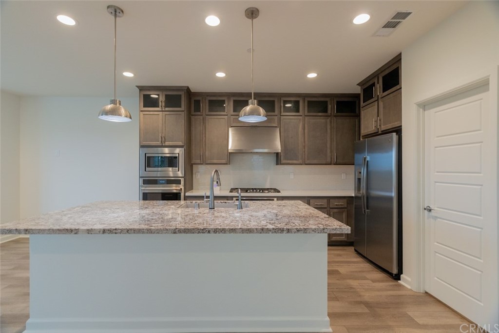 32151 Everview Temecula, CA 92591 - Photo 4 of 29 a large kitchen with kitchen island a large counter top stainless steel appliances and cabinets