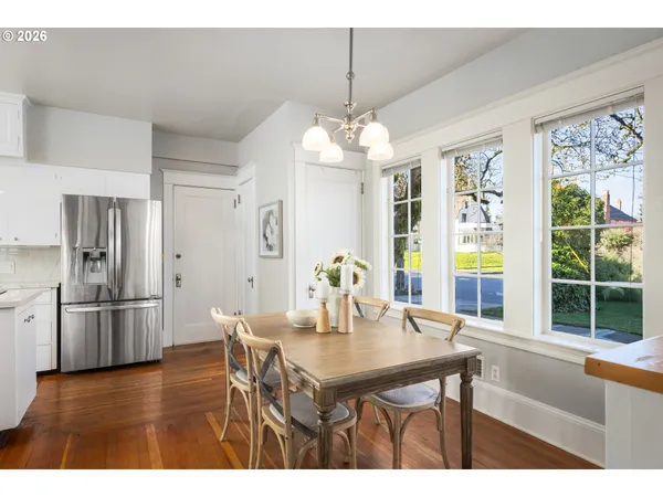 a dining room with stainless steel appliances granite countertop furniture a chandelier and wooden floor