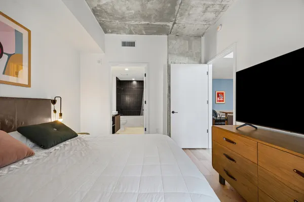a bedroom with a bed and flat tv screen on the dresser