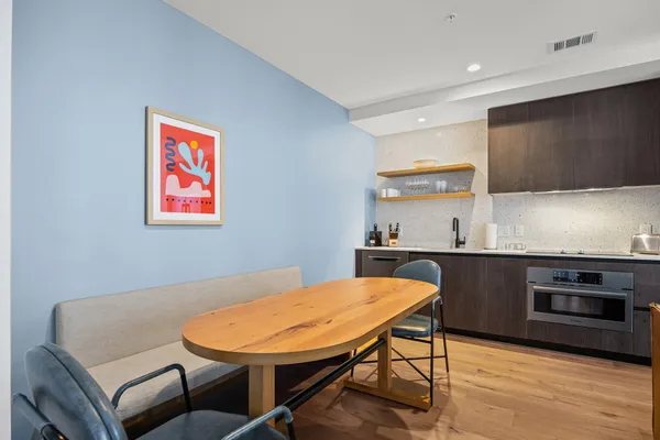 a kitchen with stainless steel appliances kitchen island granite countertop a sink a microwave cabinets and a dining table