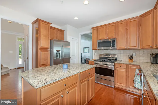 a kitchen with stainless steel appliances granite countertop a stove top oven a sink and dishwasher a refrigerator with wooden floor