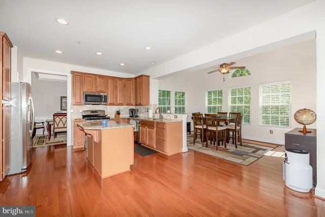 a kitchen with stainless steel appliances kitchen island wooden floors and white cabinets