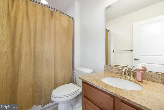 a bathroom with a granite countertop sink toilet and a mirror