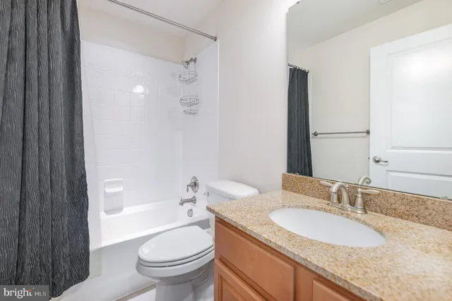 a bathroom with a granite countertop toilet a sink and a large mirror