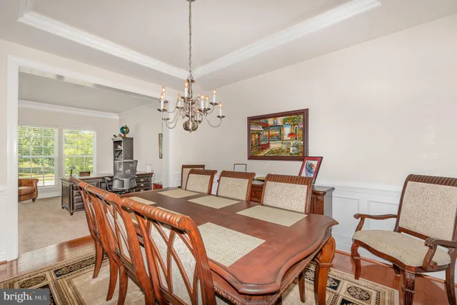 a view of a dining room with furniture a chandelier and large windows
