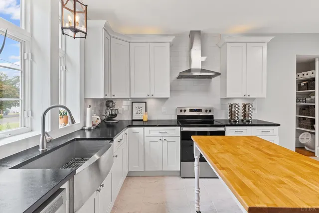 a large kitchen with granite countertop a stove and white cabinets
