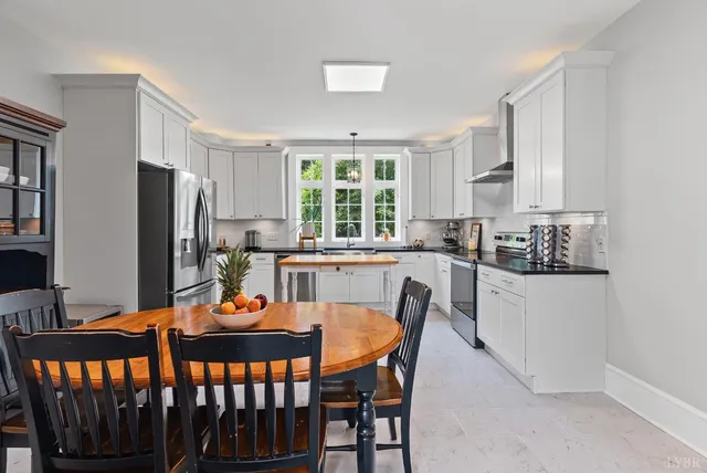 a kitchen with stainless steel appliances kitchen island a table and chairs in it