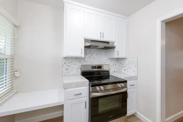 a kitchen with stainless steel appliances a stove and white cabinets