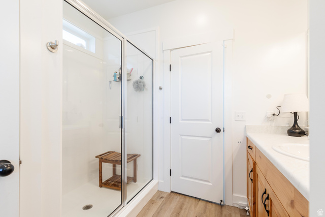 349 West 3085 South Logan, UT 84321 - Photo 18 of 37 Glass-enclosed shower with white surround, featuring a transom window, wood-finish flooring, and a vanity with a white countertop