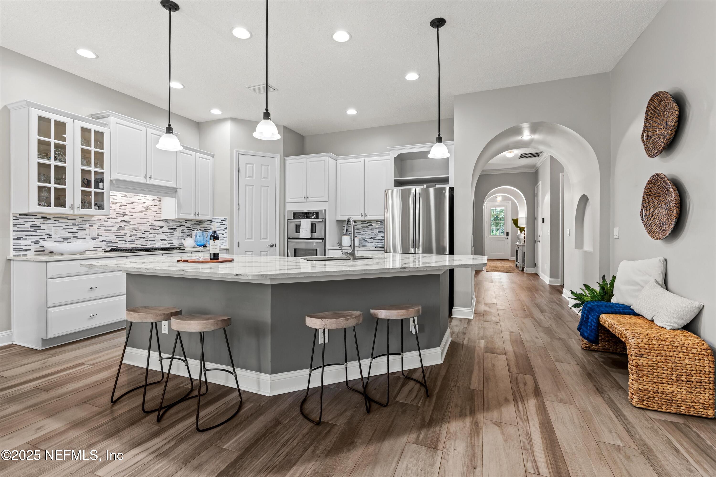 30 Pelican Pointe Road Ponte Vedra, FL 32081 - Photo 11 of 66 a kitchen with kitchen island stainless steel appliances a dining table chairs sink and wooden floor
