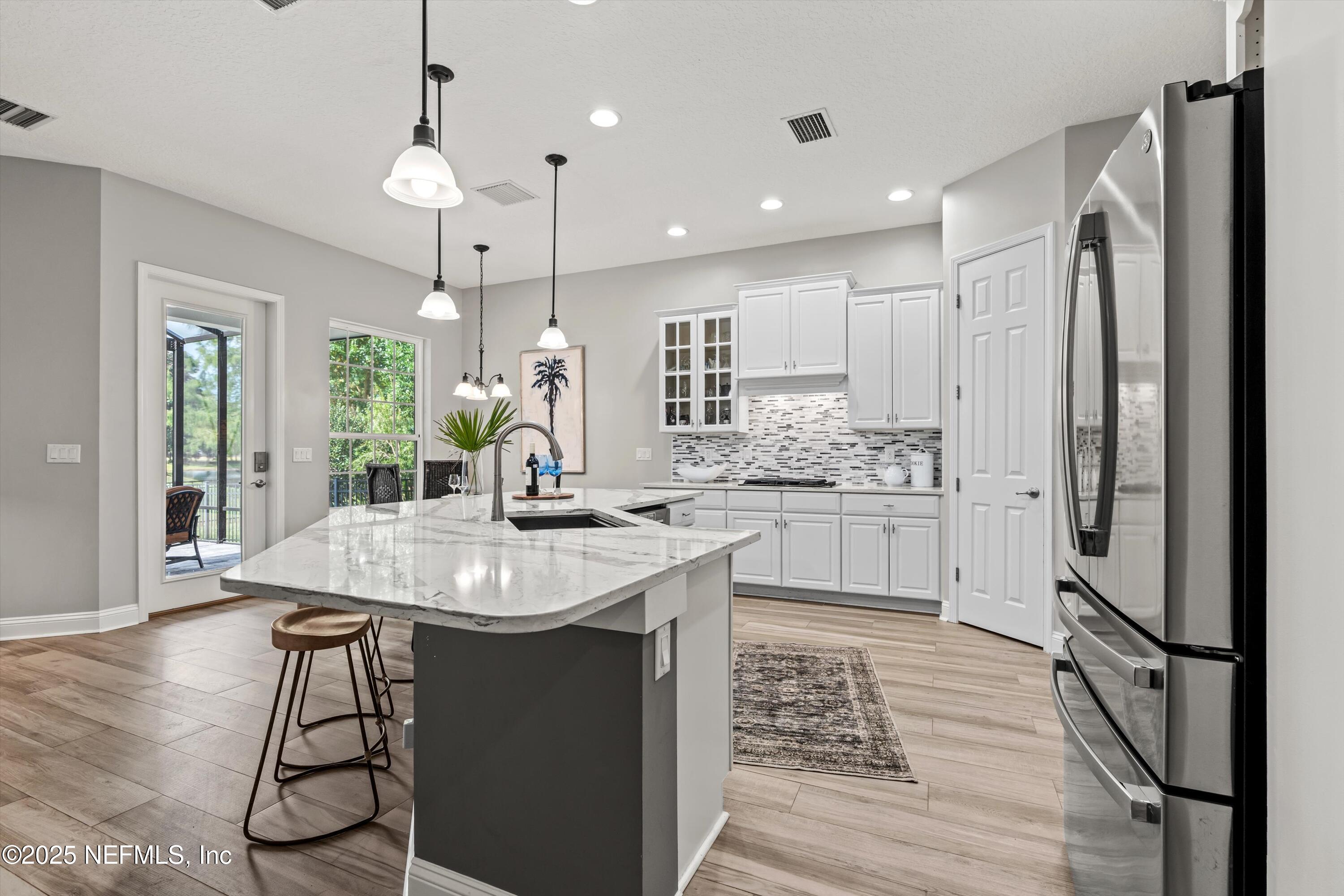 30 Pelican Pointe Road Ponte Vedra, FL 32081 - Photo 9 of 66 a kitchen with stainless steel appliances kitchen island granite countertop a refrigerator a sink dishwasher a stove and white cabinets with wooden floor