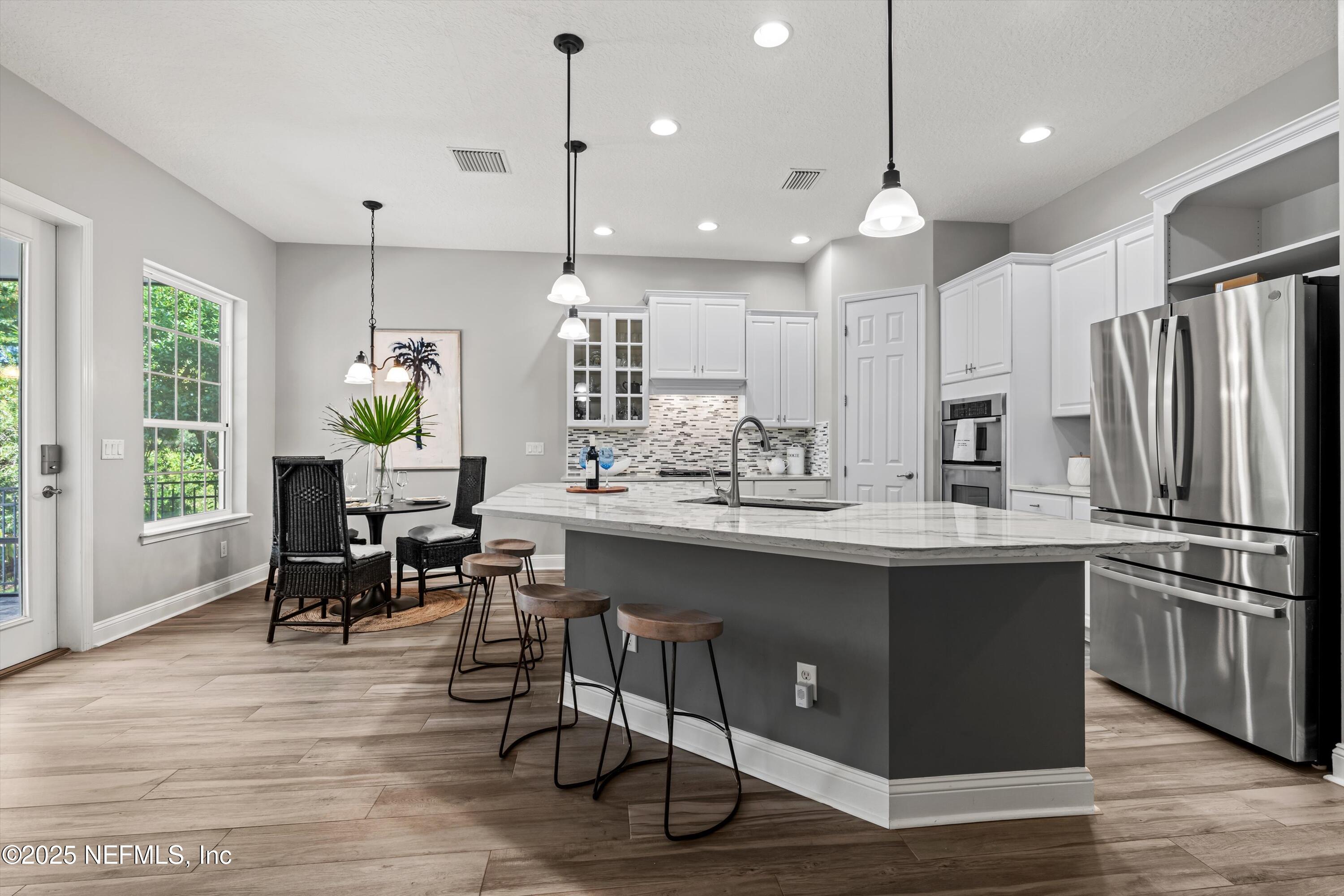 30 Pelican Pointe Road Ponte Vedra, FL 32081 - Photo 10 of 66 a kitchen with kitchen island a dining table chairs sink and wooden floor