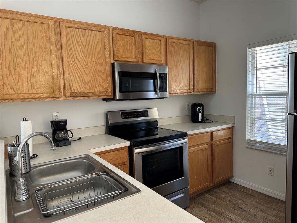 8411 Crystal Cove Loop Kissimmee, FL 34747 - Photo 13 of 43 a kitchen with granite countertop wood cabinets stainless steel appliances and a window