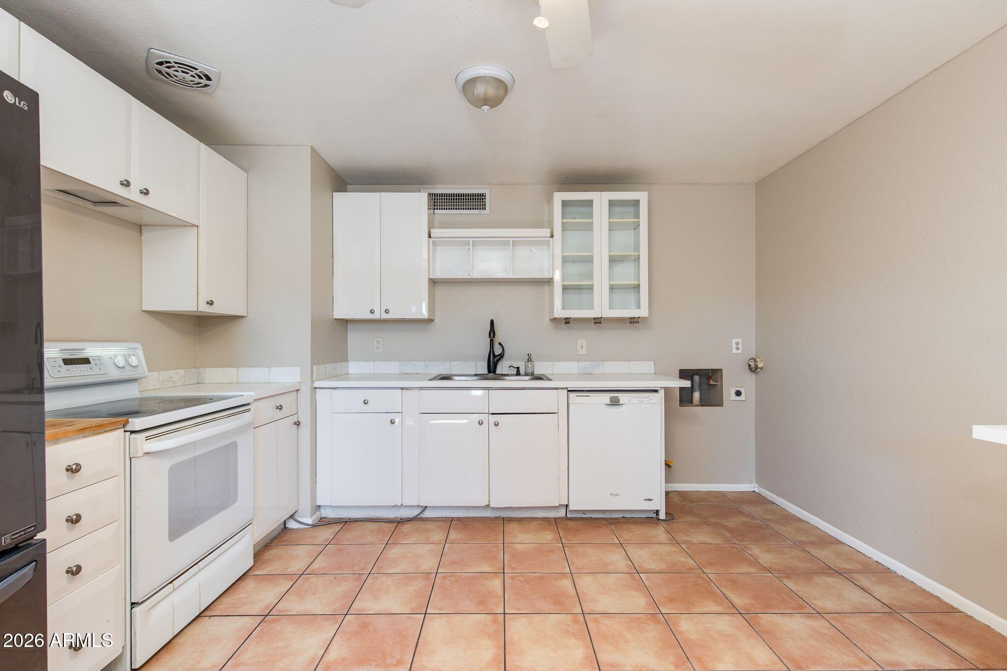 4415 East Chambers Street Phoenix, AZ 85040 - Photo 16 of 33 a kitchen with white cabinets appliances and a sink