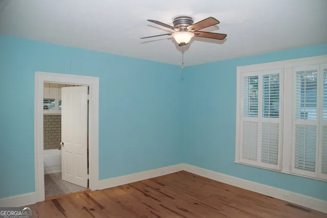 an empty room with wooden floor closet and fan