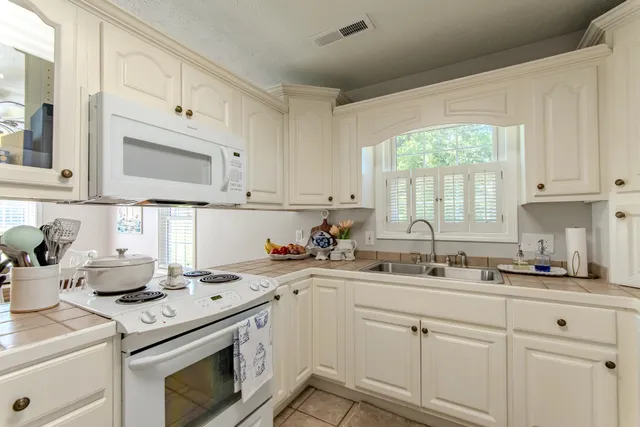 a kitchen with cabinets appliances a sink and a window