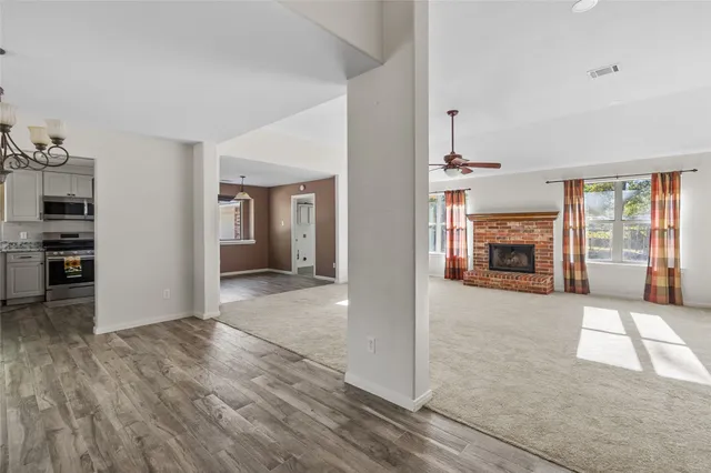 an empty room with wooden floor fireplace and windows