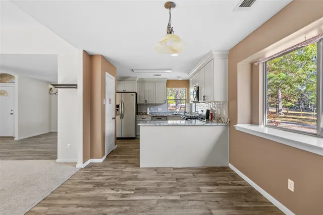 a view of kitchen with stainless steel appliances granite countertop a refrigerator a sink dishwasher a stove and white countertops with wooden floor