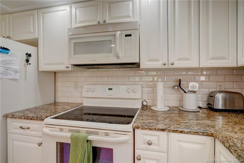 2950 Southeast Ocean Boulevard, Unit 1211 Stuart, FL 34996 - Photo 12 of 61 a kitchen with granite countertop white cabinets and a stove