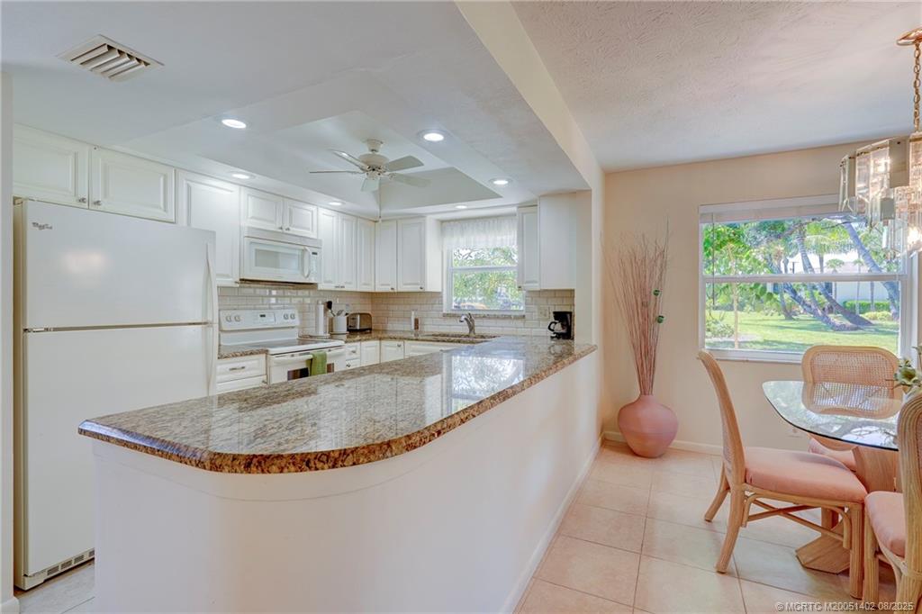 2950 Southeast Ocean Boulevard, Unit 1211 Stuart, FL 34996 - Photo 14 of 61 a kitchen with stainless steel appliances granite countertop a sink a stove a refrigerator a microwave oven with a dining table and chairs