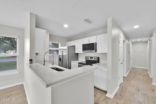 a kitchen with stainless steel appliances a sink a stove a refrigerator a center island and furniture