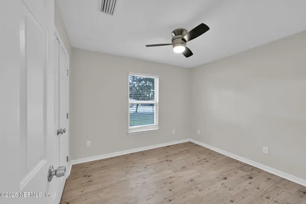 an empty room with a window and a ceiling fan