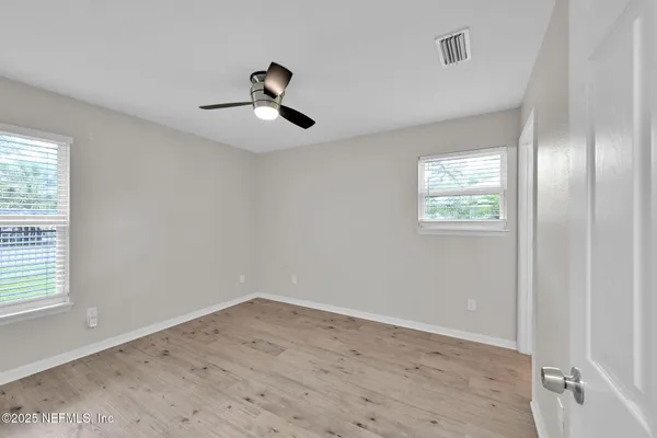 a view of empty room with wooden floor and fan