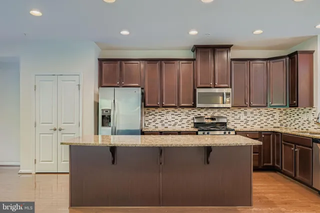 a kitchen with stainless steel appliances granite countertop a stove a sink and a refrigerator with wooden floor