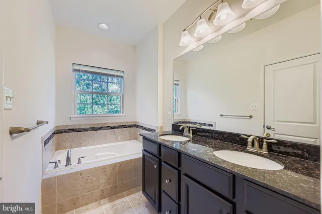 a bathroom with a granite countertop bathtub a sink and a mirror