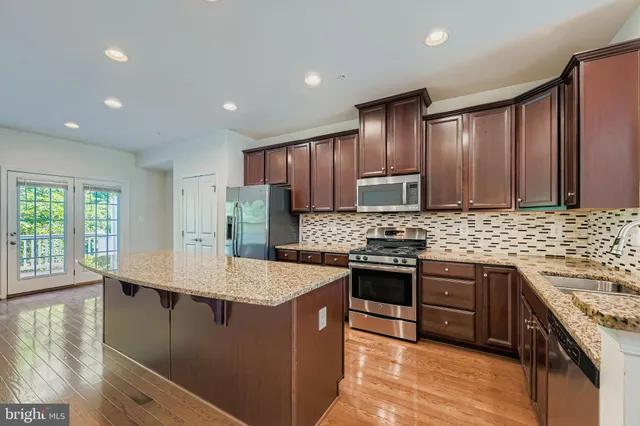 a kitchen with stainless steel appliances granite countertop wooden cabinets a stove top oven a sink and dishwasher with wooden floor