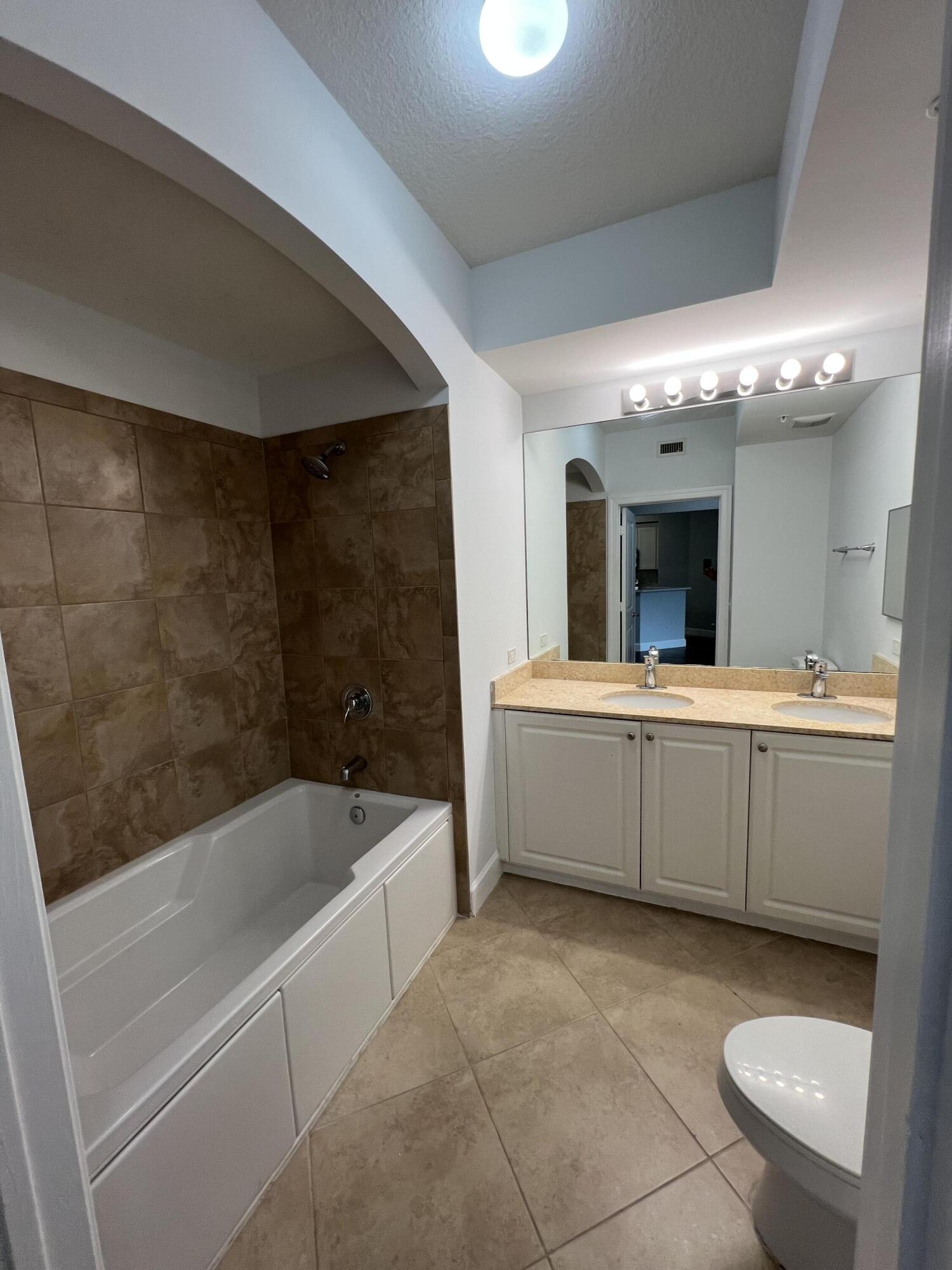 1660 Renaissance Commons Boulevard, Unit 2218 Boynton Beach, FL 33426 - Photo 18 of 23 a bathroom with a bathtub sink and mirror